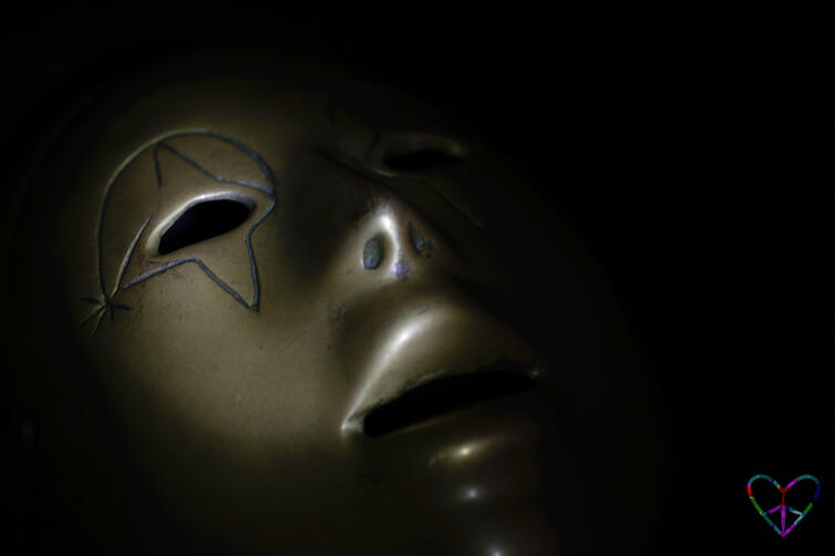 A moody close-up of a shadowed bronze mask