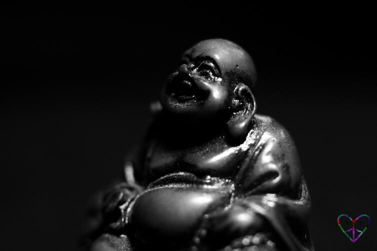 A moody shaded macro shot of a smiling Buddha
